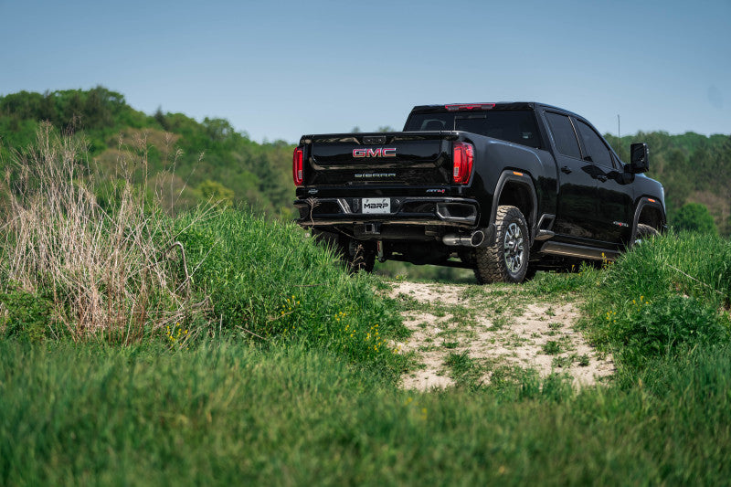 GMC truck with off-road tires on dirt path in rural setting