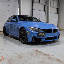 Load image into Gallery viewer, Mishimoto 15-20 BMW F8X M3/M4 License Plate Relocation Kit installed on a blue BMW for enhanced performance car tuning.