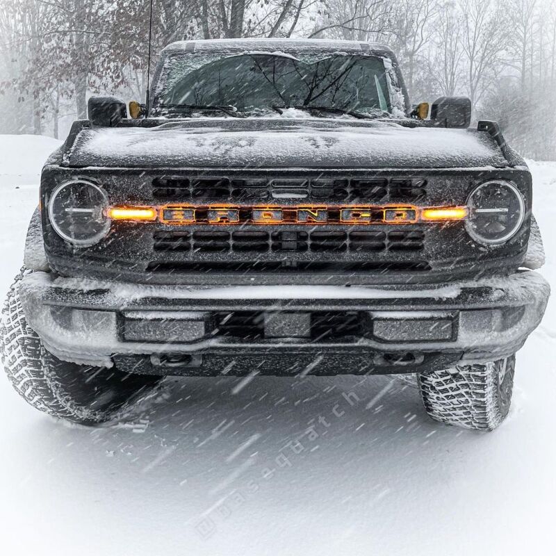 Snow-covered SUV with illuminated orange grille.