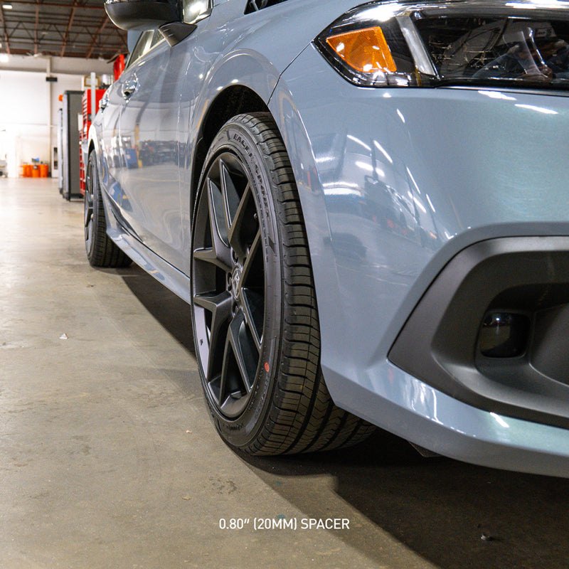 Car with Mishimoto 5X114.3 20MM Wheel Spacers for enhanced performance, shown in a garage setting. Ideal for high performance auto parts.