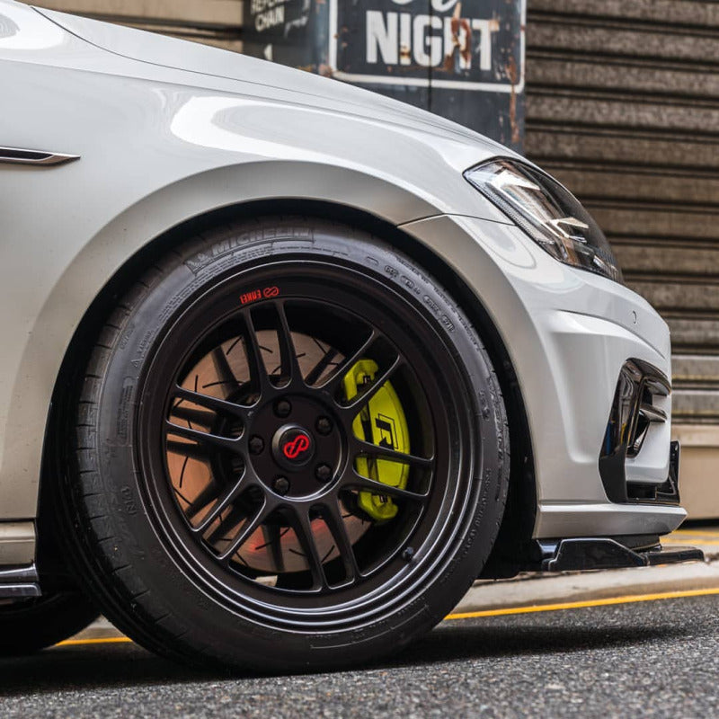 High-performance car with racing wheels and brake upgrades on an urban street at night, showcasing sleek design and advanced tuning.