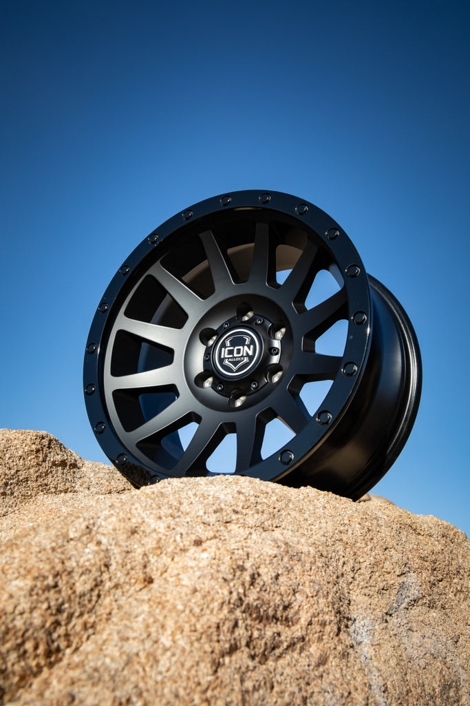 ICON Compression 17x8.5 6x5.5 25mm Offset 5.75in BS 95.1mm Bore Double Black Wheel showcased on rocks with blue sky background