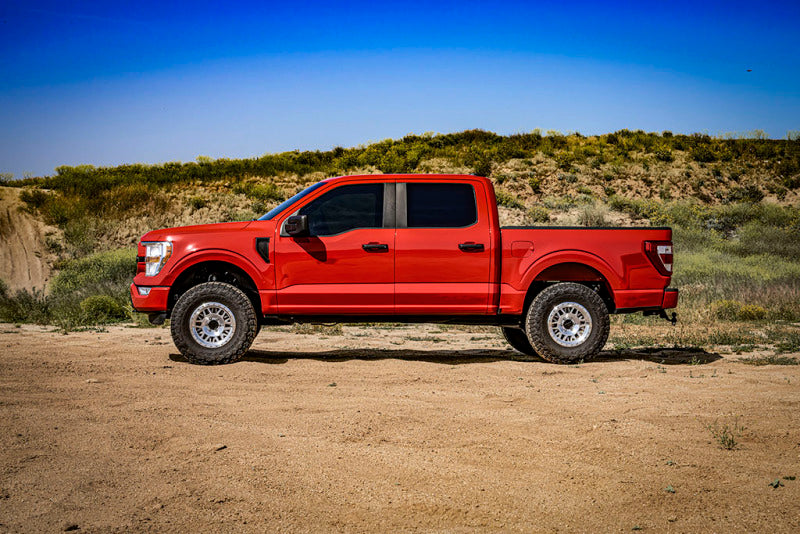 Red Ford truck displaying ICON 21-23 Ford F150 Tremor 2.5-3in 2.5 Series VS RR CDCV Coilover Kit on desert terrain.